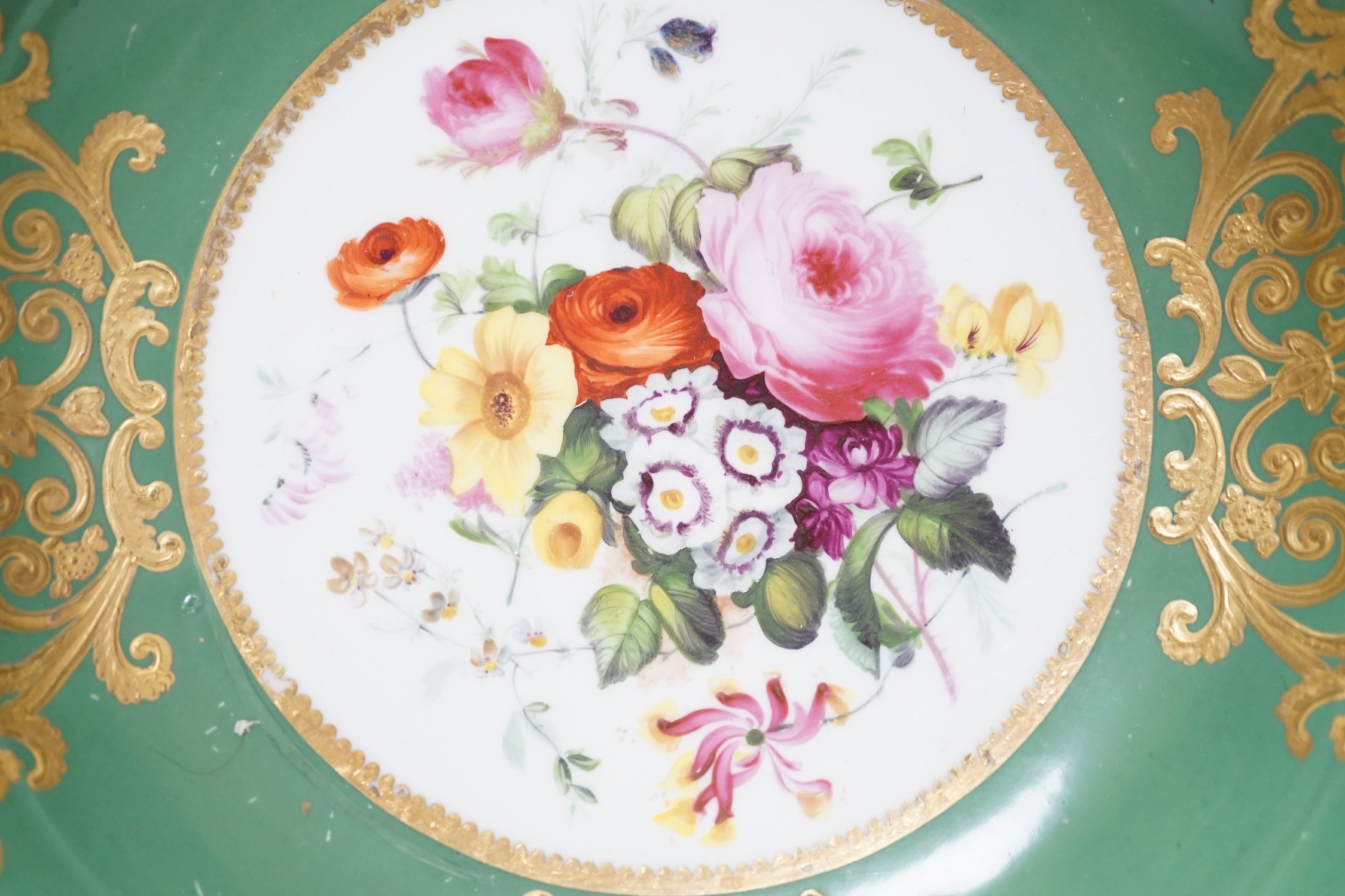 An English porcelain large bowl the centre painted with a bouquet of flowers under a green border with four ornately gilded designs, c.1820, 28cms diameter